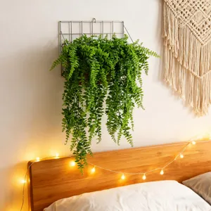 Detailed view of artificial hanging fern plant in metal basket, ideal for wall home decor.