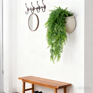Artificial fern wall hanging detail, realistic green foliage in white pot for home decor.