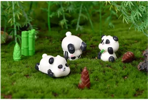 Nahaufnahme niedlicher Miniatur-Harz-Panda-Figuren mit Bambus und Moos-Landschaftsdetails.