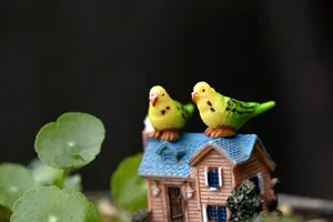 Miniature resin parrot ornament close-up, cute micro landscape potted plant decor detail.