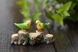 Close-up view of cute resin parakeet bird figurines on tree stumps for DIY landscaping decor.