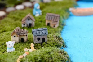Vue de détail en gros plan de maisons miniatures en résine et ornements pour plantes en pot.