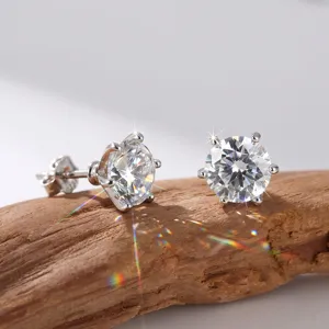 Makrodetail von eleganten 14K Gold Labordiamant-Ohrsteckern auf einem natürlichen Holzhintergrund