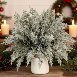 Gedetailleerd overzicht van bevroren kunstmatige dennentakken met witte keramische vaas voor kerst.
