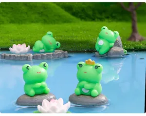 Vista detallada de adorables estatuillas de ranas de resina para decoración de escritorio.