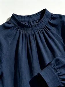 Close-up of dark blue linen blouse collar and pleated details, elegant and soft style.
