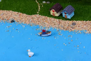Micro landscape miniature blue sand scene detail showing small houses and cute boat decor.