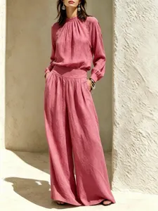 Close-up of the elegant pink long-sleeve pleated top and wide-leg trousers outfit details.