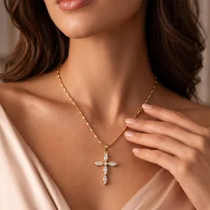 Close-up of gold stainless steel cross necklace with marquise-cut zirconia on model.