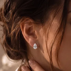 Detaillierte Nahaufnahme eines birnenförmigen Diamantohrrings am Ohr im Sonnenlicht
