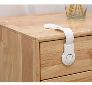 Close-up of a white adjustable child safety strap lock installed on a wooden drawer