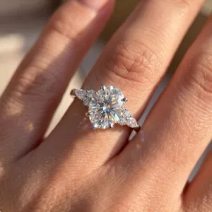 Nahaufnahme eines funkelnden Moissanit-Rings im Ovalschliff mit Seitensteinen am Finger im Licht