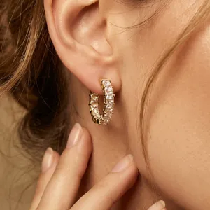 Primer plano detallado de pendientes de aro dorados con pavé de cristales.