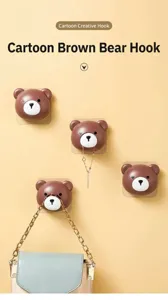 Detailed view of cute cartoon bear wall hooks holding a handbag and necklace