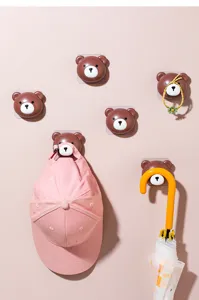 Detail view of cute brown bear adhesive wall hooks holding various household items