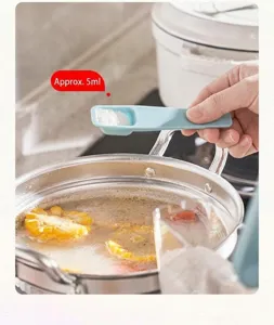 Detailed view of a light blue 5ml measuring spoon adding salt to a simmering pot