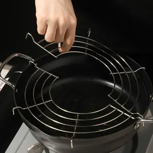 Nahaufnahme eines halbrunden Ölabtropfgestells aus Edelstahl auf einem schwarzen Topf.