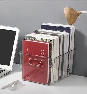 Close-up of a clear plastic storage box organizing books on a modern desktop.