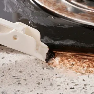 White handheld kitchen crevice cleaning brush scraping burnt grease off a gas stove