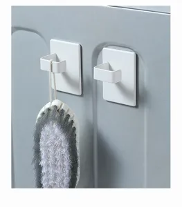Detailopname van witte magneethaken met een schoonmaakborstel op grijs oppervlak.