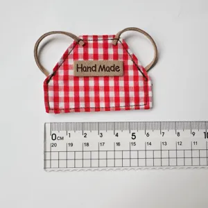 Mini delantal de muñeca a cuadros rojos y blancos con correas de cuero para ropa.