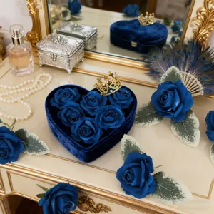 Blue artificial velvet rose flower heads detail scene with heart velvet box and crown decor.