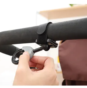 Primer plano de un gancho para cochecito sujeto al manillar con una correa de velcro.