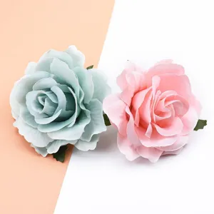Nahaufnahme von zarten geflockten Stoff-Rosenblüten in Pastellgrün und Rosa für DIY-Haarschmuck.
