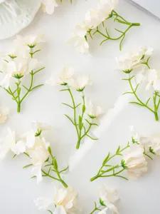 Close-up detail of artificial white mini orchid floral accessories with green stems for DIY crafts.