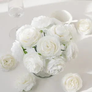 Close-up detail of white silk peony flowers bouquet with glass vase and elegant table setting props.