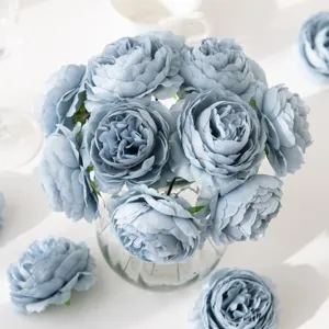 Close-up detail of dusty blue artificial peony silk flowers arrangement in a glass vase.