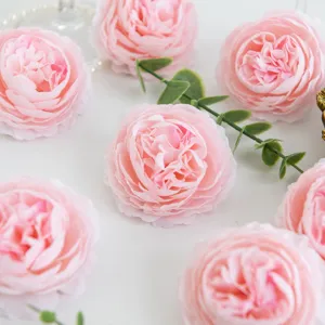 Close-up detail of artificial pink peony silk flowers with green leaves for decoration.