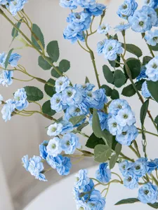 Detail shot of long stem artificial small rose flowers, blue decorative floral prop for home decor.
