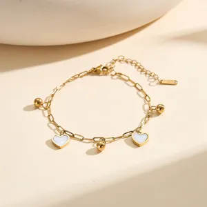 Detail shot of a gold stainless steel bracelet with heart charms and ball pendants