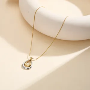 Detalle de collar con colgante de lágrima bicolor con diseño en dorado y plateado