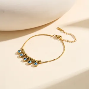 Close-up of 18K gold-plated stainless steel bracelet featuring five blue evil eye charms.