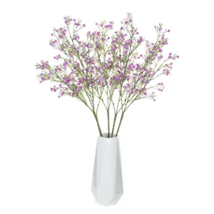 Detailed view of artificial purple gypsophila bouquet in white geometric vase for home decor.