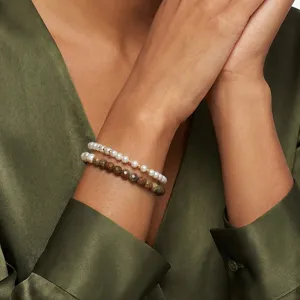 Detailansicht von geschichteten Perlen- und Türkisperlenarmbändern am Handgelenk