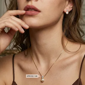Nahaufnahme einer eleganten Gold-Perlenkette und Ohrstecker, getragen von einem Modell