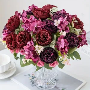 Artificial burgundy rose peony flower bouquet in glass vase for home decoration.
