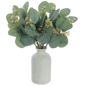Artificial eucalyptus leaves with pink flower buds in white ceramic vase for decor.