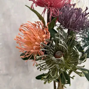 Nahaufnahme künstlicher Nadelkissenblüten in Vintage-Farben mit feinen Texturen und Details.