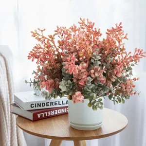 Detailed close-up view of artificial autumn eucalyptus plant and flower arrangement in pot.
