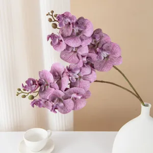 Dettaglio ravvicinato di rami di orchidee phalaenopsis artificiali in vaso bianco per casa.