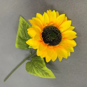 Détail de tournesol artificiel unique avec des pétales jaunes vibrants et des feuilles vertes.