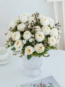 Detailaufnahme eines künstlichen weißen Rosenstrauchs in einer Glasvase als Dekoration.