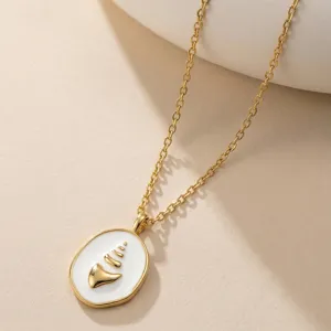 Detailaufnahme einer Vintage-Goldkette mit weißem Emaille-Muschelanhänger im Retrostil