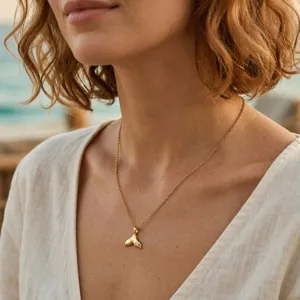Nahaufnahme einer goldenen Meerjungfrauenschwanz-Halskette an einem Modell am Strand.