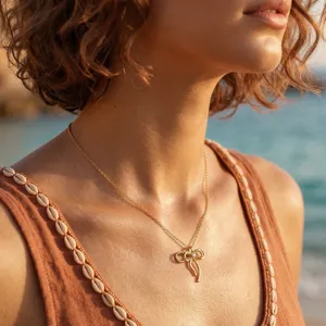 Detailaufnahme einer zarten goldenen Schleifenkette mit Zirkonia am Hals eines Models.