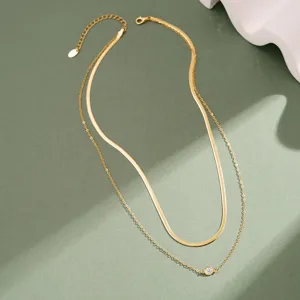 Détail d'un collier doré à deux rangs avec un pendentif délicat en zircone